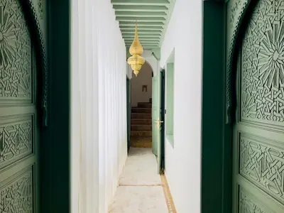 a hallway with green doors and a chandelier at Riad Kaya in Marrakech