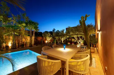 a wooden table and chairs next to a swimming pool at Villa Nomade - 4 BR BA - Piscine - Parking - Ourika in Sraghna