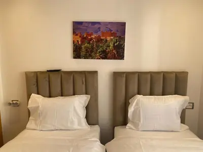 two beds with white pillows and a painting above them at Cozy apartment with pool Bd Mohamed 6 in Marrakech
