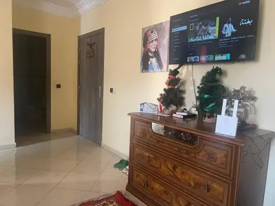 a room with a television on top of a wooden dresser at Appartement a côté Aéroport Menara marrakech in Marrakech