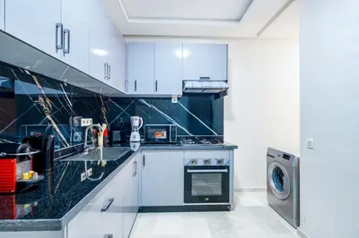 a kitchen with white cabinets and a washer and dryer at Comfort and Serenity in the Center of Marrakech in Marrakech