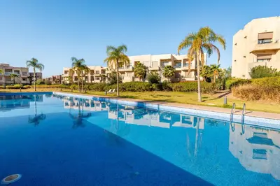 a large swimming pool with palm trees and condos at 2-Bedroom Residence Jubeae - Pool & Golf Nearby in Marrakech
