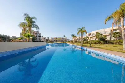 a large swimming pool with palm trees and buildings at 2-Bedroom Residence Jubeae - Pool & Golf Nearby in Marrakech