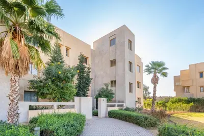 a building with palm trees in front of it at 2-Bedroom Residence Jubeae - Pool & Golf Nearby in Marrakech