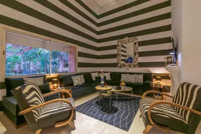 a living room with a green couch and a striped wall at Oasis - 7 min from Majorelle - Medina and Nightlife with AC and Pool in Marrakech
