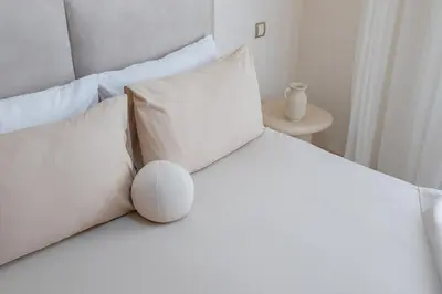 a white bed with white pillows and a table at Downtown Gueliz Modern 1BR AC, Fast WIFI , Parking in Marrakech