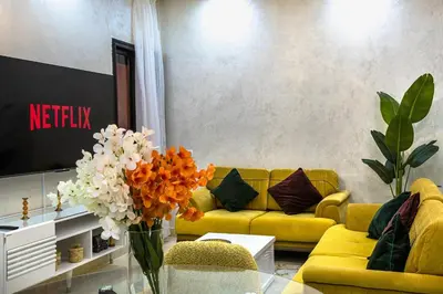 a living room with a yellow couch and a vase of flowers at Appartement Bien équipé au Centre ville Garage Privé et Climatiseur Fibre 5G in Marrakech
