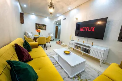 a living room with a yellow couch and a television at Appartement Bien équipé au Centre ville Garage Privé et Climatiseur Fibre 5G in Marrakech