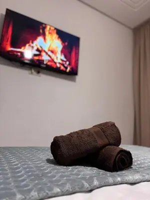 a towel laying on a bed with a tv on the wall at The Cristal House in Marrakech