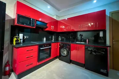 a red kitchen with a washing machine and a microwave at Opéra A Studio Apartment in Marrakech