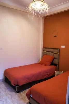 a bedroom with two beds and a chandelier at Appartement privatisé Gazelles MsHolidays Marrakech in Marrakech