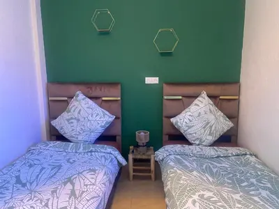 a room with two beds and a green wall at Appartement privatisé Gazelles MsHolidays Marrakech in Marrakech