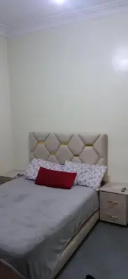 a bedroom with a large bed with a red pillow at appartement meublé accoté de l aéroport Marrakech in Marrakech