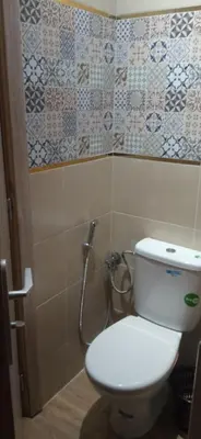 a bathroom with a toilet and tiles on the wall at appartement meublé accoté de l aéroport Marrakech in Marrakech