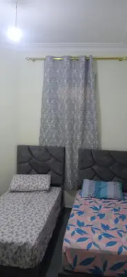 a bedroom with two beds and a window with a curtain at appartement meublé accoté de l aéroport Marrakech in Marrakech