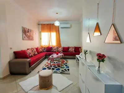 a living room with a red couch and a table at Stylish & Bright Apartment in Marrakech