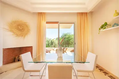 a dining room with a glass table and white chairs at Luxurious Apartment in Marrakech in Dar Caïd Layadi