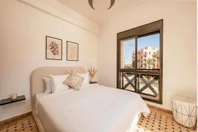 a white bedroom with a bed and a window at Cozy & Stylish Apartment in Marrakech in Marrakech