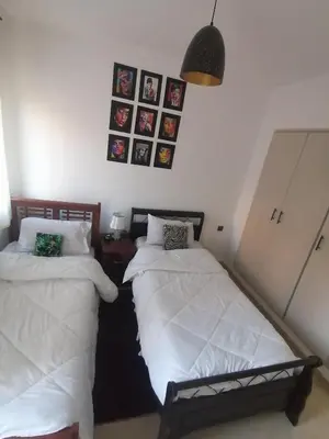 two beds in a room with pictures on the wall at Appartement cosy in Marrakech