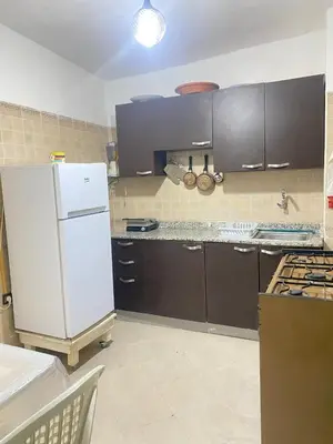 a kitchen with a white refrigerator and brown cabinets at Appartement cosy in Marrakech