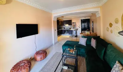 a living room with a green couch and a flat screen tv at Résidence Miramas 2 Cosy Appartment 2 in Marrakech