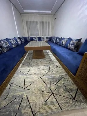 a living room with a blue couch with a table at Appartement 2 chombr salon a marrakech in Marrakech