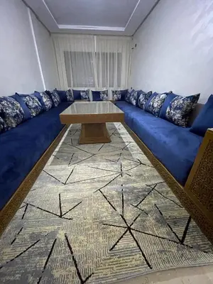 a living room with a blue couch with a table at Appartement 2 chombr salon a marrakech in Marrakech
