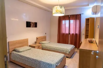 a bedroom with two beds and a chandelier at Two Bedroom Luxury Appt with air conditioning parking and pool in Marrakech