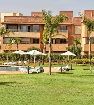 a resort with a pool and chairs and umbrellas at Luxueux Appartement Prestigia Agate in Marrakech
