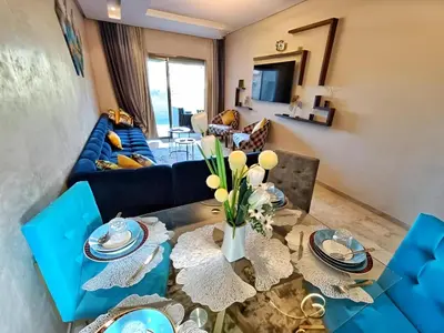 a living room with a blue couch and a table at Luxueux Appartement Prestigia Agate in Marrakech