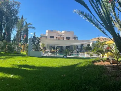 a large house with a green lawn in front of it at Villa Souzana in Marrakech