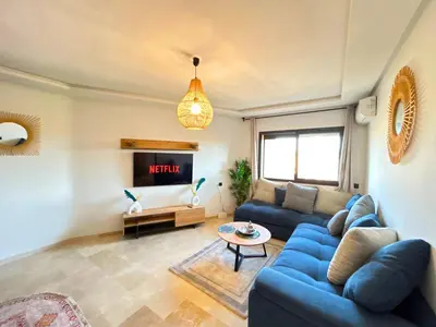 a living room with a blue couch and a tv at Le Cosy de Gueliz avec Piscine et Belle Vue in Marrakech