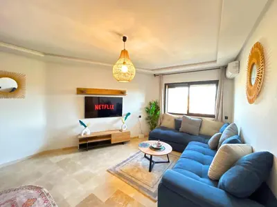 a living room with a blue couch and a tv at Le Cosy de Gueliz avec Piscine et Belle Vue in Marrakech