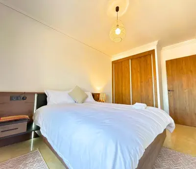 a bedroom with a large white bed with a light at Le Cosy de Gueliz avec Piscine et Belle Vue in Marrakech