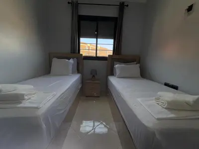 two twin beds in a room with a window at charming apartment close to airport Marrakech in Marrakech