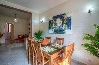 a dining room table with chairs and a painting on the wall at Spacious and Family Apartment in Marrakech