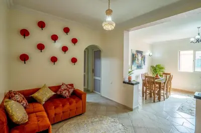 a living room with an orange couch and red umbrellas on the wall at Spacious and Family Apartment in Marrakech