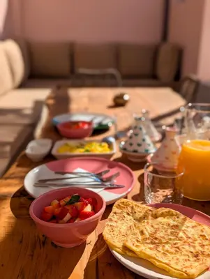 a wooden table topped with plates of food and toast at Riad Doll LallaZwina in Marrakech