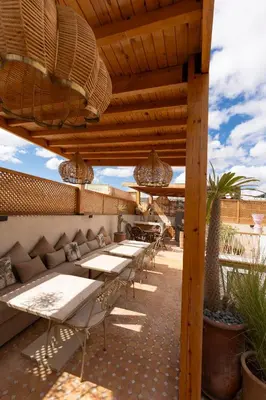 a patio with tables and chairs under a wooden pergola at Riad Rumi Marrakech Medina in Marrakech