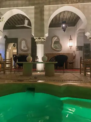 a pool in a room with a table and chairs at riad medina marrakech in Marrakech