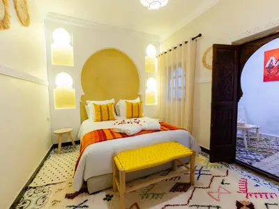 a bedroom with a large bed and a yellow bench at Riad Dar Lamia Marrakech Médina in Marrakech