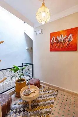 a living room with a table and a painting on the wall at Riad Dar Lamia Marrakech Médina in Marrakech