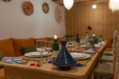 a long wooden table with glasses and a blue vase on it at Riad Dar Lamia Marrakech Médina in Marrakech
