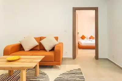 a living room with a couch and a bed at Suite Mandarine - Charme et confort chaleureux in Marrakech