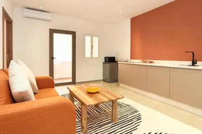 a living room with a couch and a table and a kitchen at Suite Mandarine - Charme et confort chaleureux in Marrakech