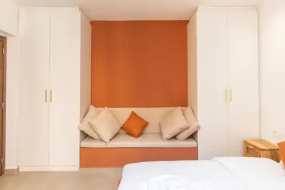 a bedroom with white cabinets and a bench with pillows at Suite Mandarine - Charme et confort chaleureux in Marrakech