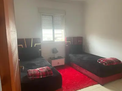 a bedroom with two beds and a red carpet at MmAéroport Menara Résidence abrar mhamid 1 in Marrakech