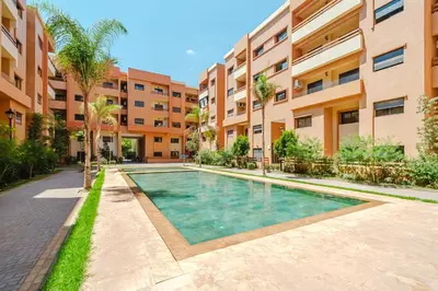 an apartment complex with a swimming pool in front of a building at Modern Appart , Parking , Pool & Fiber wifi , Hivernage City Centre in Marrakech