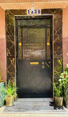 a large black door with plants in front of it at Cozy Moroccan-style apartment in Marrakech