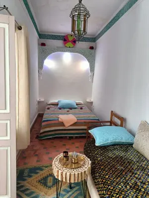 a room with two beds and a table in it at Dar Le Monde in Marrakech